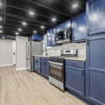 Kitchen with blue cabinetry and stainless appliances in an Affordable Living Company home