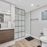 Modern bathroom with walk-in glass shower in an Affordable Living Company home