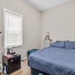 Furnished bedroom with a queen bed and dresser in an Affordable Living Company home