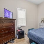 Furnished bedroom with a bed, dresser, and TV in an Affordable Living Company home