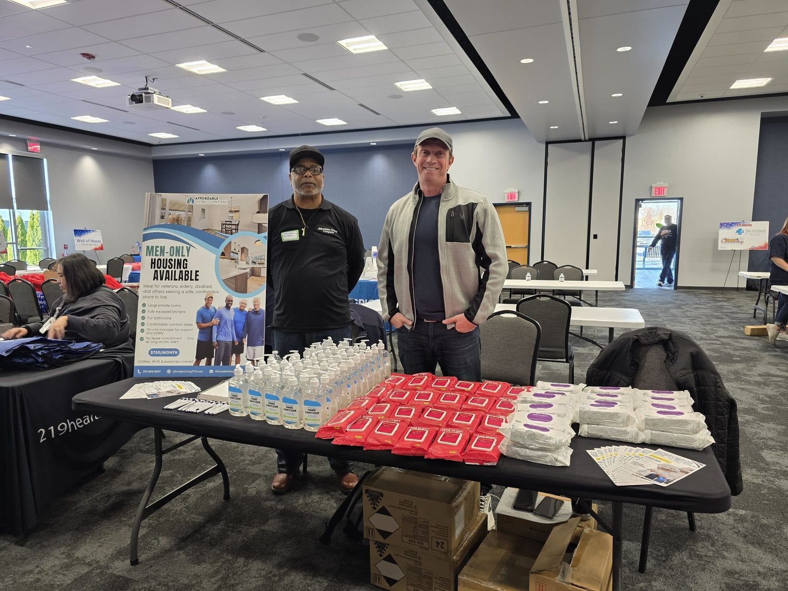 Affordable Living Company outreach booth with a men-only shared housing banner at the Northwest Indiana Military Stand Down
